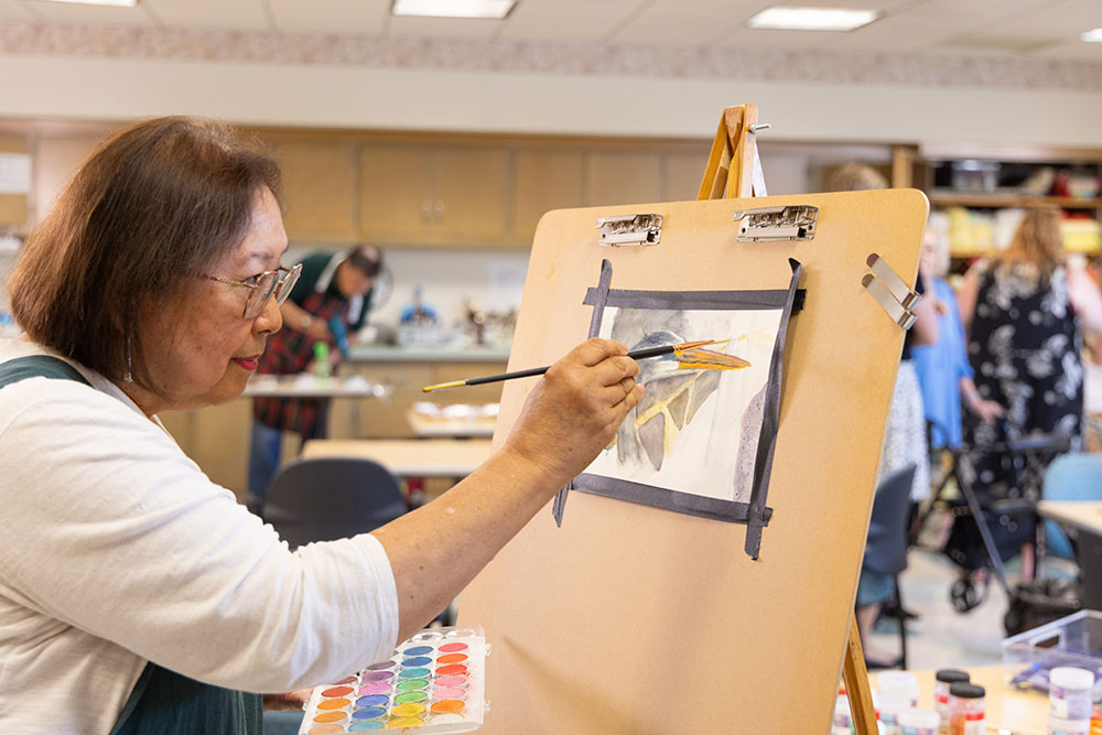 Memory care resident at Westminster Place painting a watercolor in the art studio